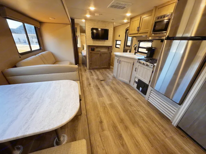 An RV rental interior reveals a modern kitchen, comfortable living area with sofa and dinette, and wood floors.. Coachmen Catalina Summit Series 8 261BHS 2025