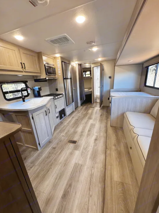 An RV rental's bright interior: modern kitchen, convertible dinette, bunk beds, and a full bathroom are visible.. Coachmen Catalina Summit Series 8 261BHS 2025