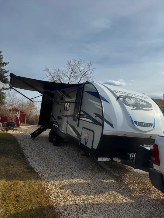 RV rental: A modern travel trailer with awning extended, parked on a gravel driveway, ready for adventure.. Forest River Cherokee Alpha Wolf 2022