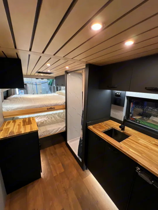 Cozy RV rental interior: kitchenette, bunk beds, and a compact shower, ideal for adventure.. Dodge Ram Promaster 2025