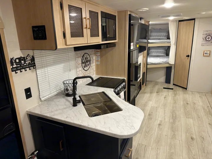 Modern RV rental interior with a fully equipped kitchen, bunk beds, and cozy details for your adventure.. Prime Time Avenger 27DBS 2024
