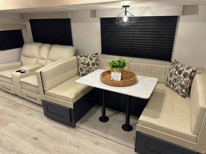 Step inside this inviting RV rental: cream Thomasville recliners, a dining booth with marble table, black blinds & light wood floors.. Prime Time Avenger 27DBS 2024