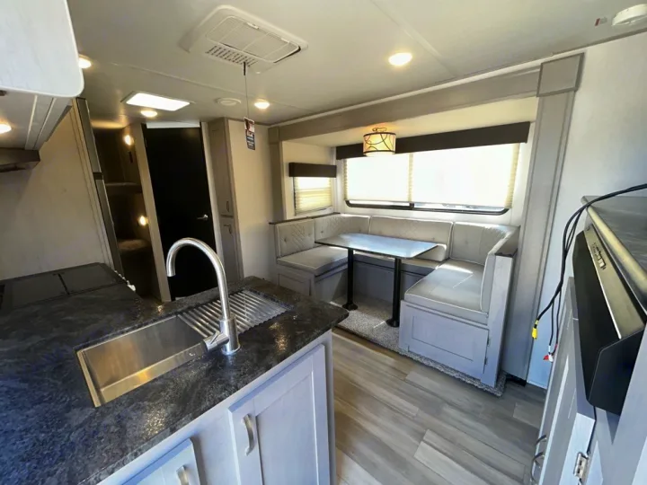 Spacious RV rental interior featuring a modern kitchen, U-shaped dinette, and cozy bunk beds. Perfect for family adventures.. Forest River Tracer 2022