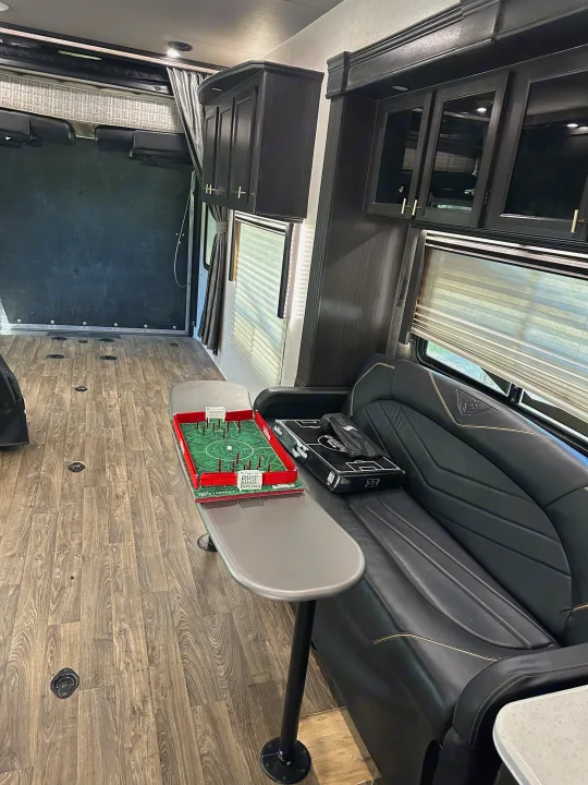 Spacious RV rental interior with wood-look flooring, plush sofa, dark cabinets, and a tabletop foosball game.. Eclipse Recreational Vehicles Attitude 2020