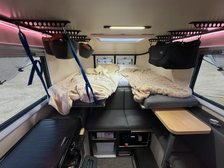 Cozy RV rental interior with two sleeping areas, overhead hanging storage, and a Dometic appliance.. Adventurer 2015 Tacoma 2024