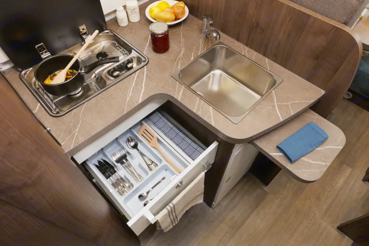 Prepare meals in a compact RV rental kitchen featuring a stovetop, sink, and an organized drawer with cooking utensils.. Benimar Tessoro 463UP 2025