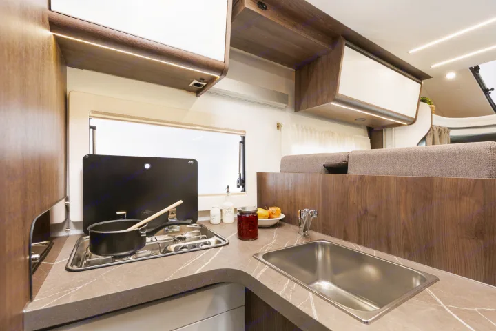 Modern RV rental kitchen with compact stove, sink, and stylish countertop. Bright overhead lighting and ample storage make camping comfortable.. Benimar Tessoro 463UP 2025