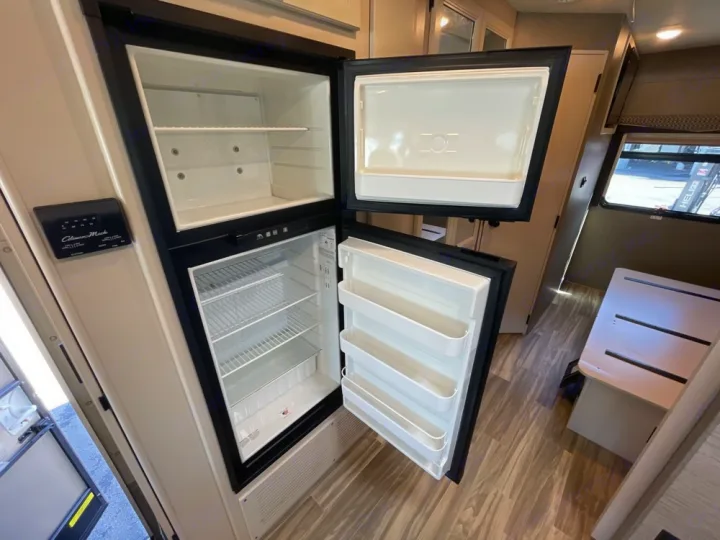 Explore this RV rental! Open refrigerator with freezer shows empty shelves, ready for your provisions in the clean interior.. Thor A.C.E. 2020