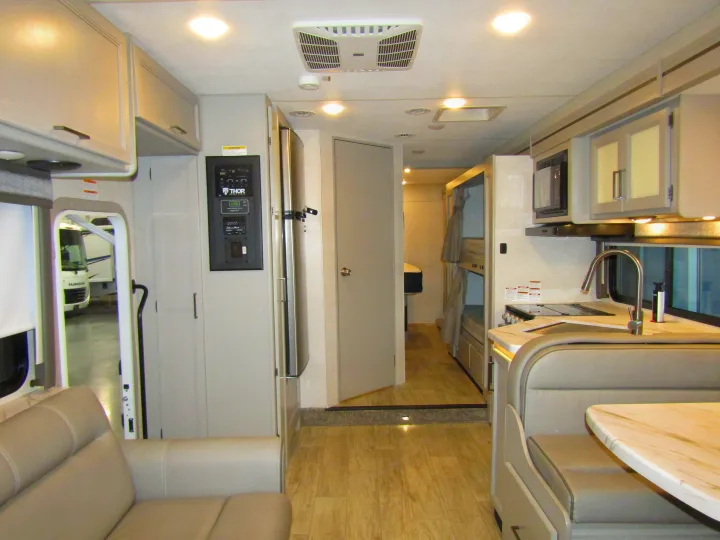 Interior of an **rv rental**: a compact yet functional living space with kitchen, dinette, and bunk beds for family travel.. Thor Chateau 2024