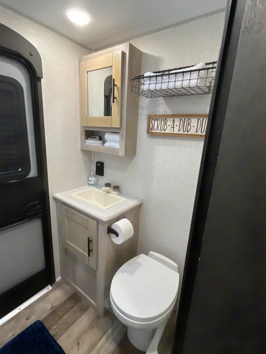 Bright rv rental bathroom with a vanity, sink, toilet, medicine cabinet, and towel storage. A functional and tidy space.. KZ Connect 2021