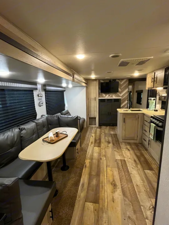 Spacious RV rental interior with modern kitchen, dining area, and living space, featuring wood-look flooring and comfortable seating.. KZ Connect 2021