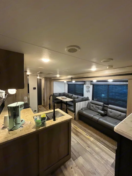 Inside a modern RV rental: open living space with kitchen, dining booth, and comfortable sofa. Your travel home awaits.. KZ Connect 2021