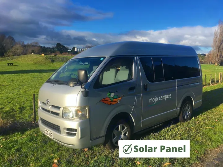 Silver campervan for RV rental by Mojo Campers, featuring a high roof and solar panel, parked in a sunny field.. Toyota Hiace 2006