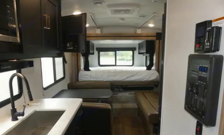 Inside an RV rental: a modern travel trailer interior with kitchenette, bed, dinette, and main control panels visible.. Keystone RV Outback Ultra-Lite 2022
