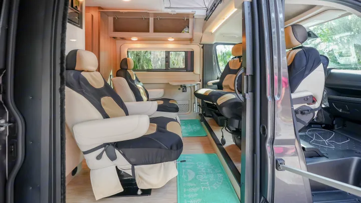 Spacious RV rental interior with cream/black swivel seats, wooden cabinetry, and floor mats, ready for comfortable travel adventures.. Jayco swift 2024