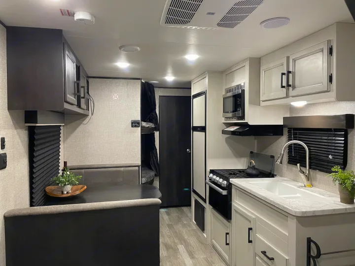 Modern RV rental interior: Full kitchen, dining booth, and bunk access offer cozy travel.. Jayco Jay Flight SLX 2022