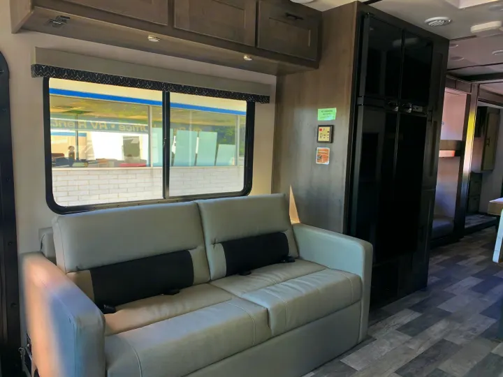 Spacious RV rental interior: Light gray sofa, large window, and modern black refrigerator within a comfortable living space.. Forest River Fr3 2025