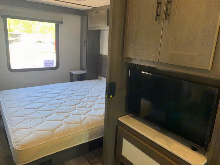 Spacious RV rental bedroom featuring a comfortable bed, window, TV, and ample storage cabinets.. Forest River Fr3 2025