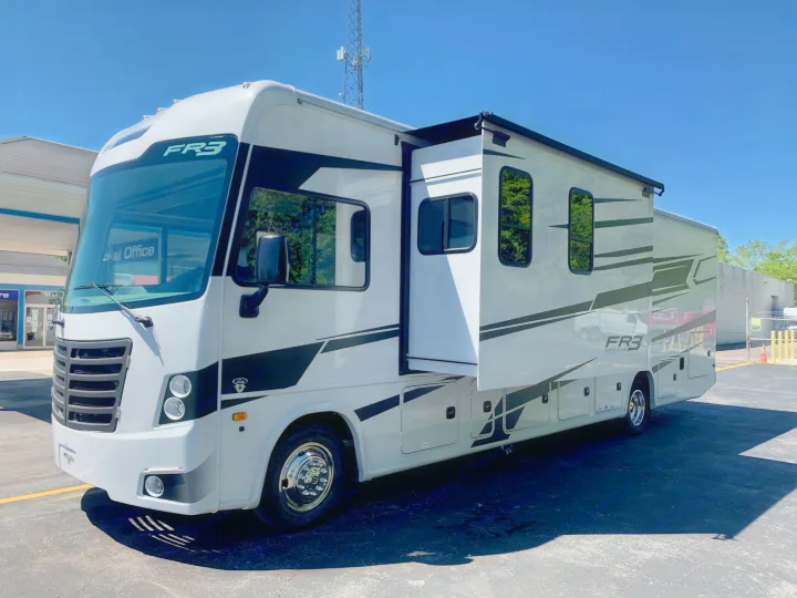 A white Forest River FR3 RV, ideal for rv rental, parked outdoors with its side slide-out extended on a sunny day.. Forest River Fr3 2025