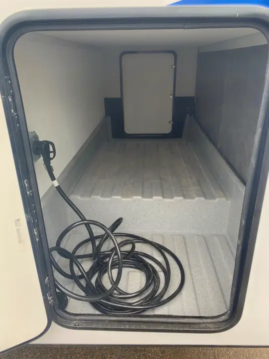 RV rental storage compartment shows an empty bay with a connected power cord, ready for your travel gear.. Forest River Sunseeker 2026