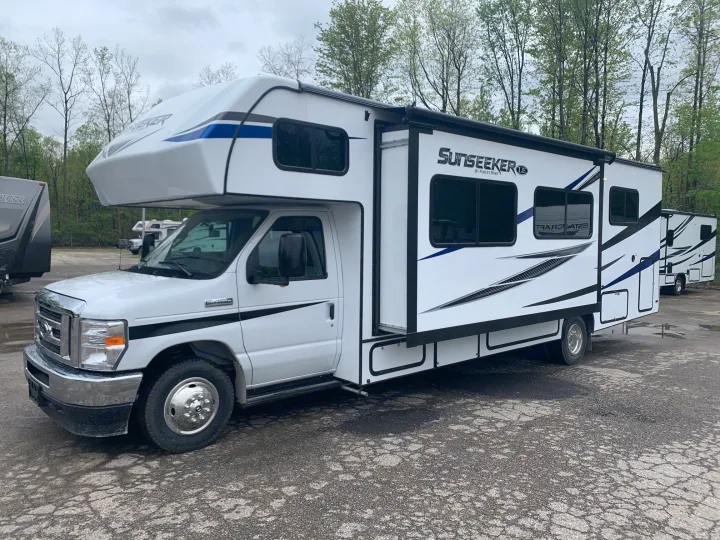 Explore with this white Sunseeker Class C RV rental, slide-out extended, parked on asphalt. Your road trip adventure awaits!. Forest River Sunseeker 2026