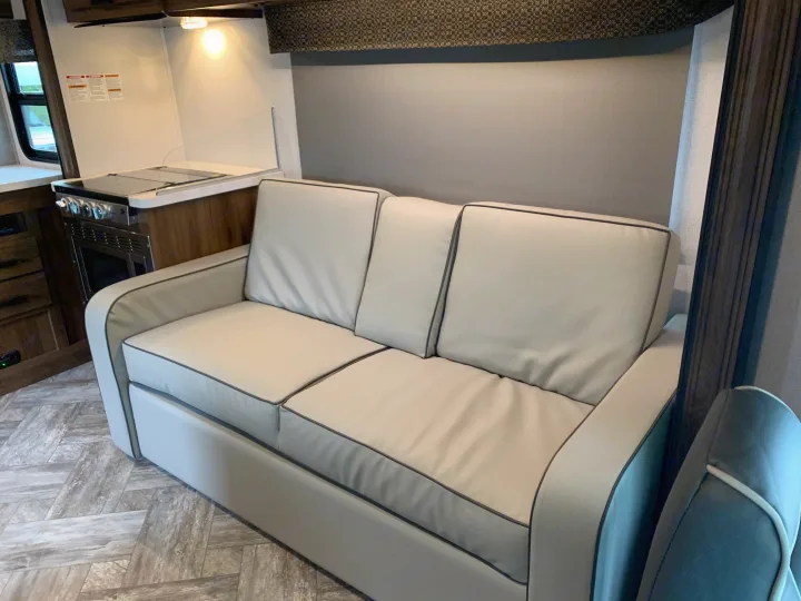 Step inside this RV rental! Features a light-colored sofa and a full kitchenette with an oven, set on wood-look floors.. Forest River Sunseeker 2026