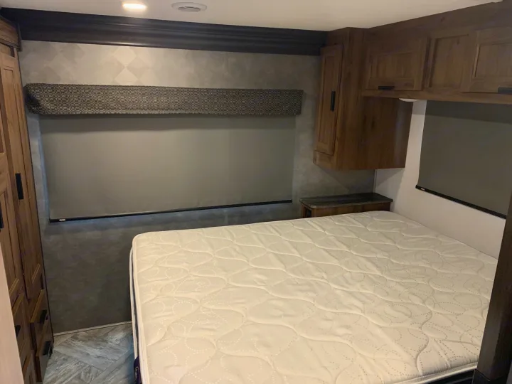 RV rental bedroom with queen mattress, dark cabinetry, and textured gray walls. Comfortable for your next adventure.. Forest River Sunseeker 2026
