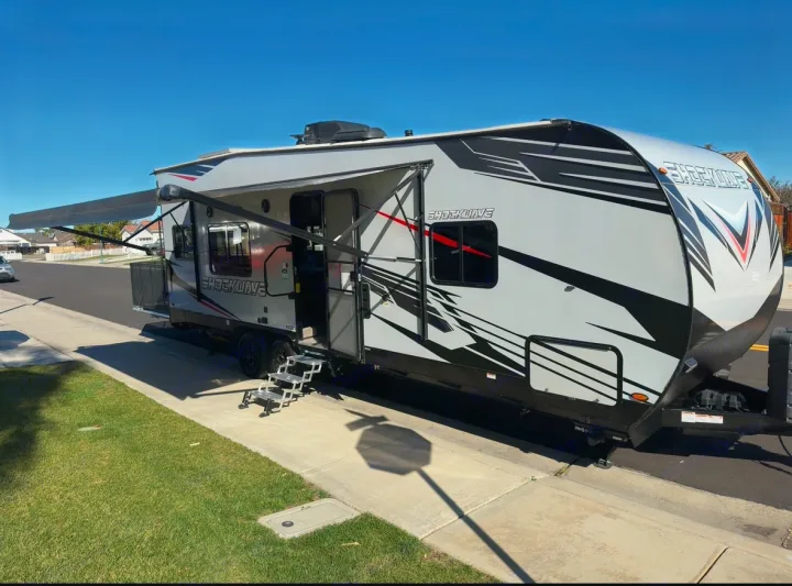 Modern Shockwave toy hauler RV rental with extended awning and convenient steps, ready for your next adventure.. Forest River Shockwave 2021