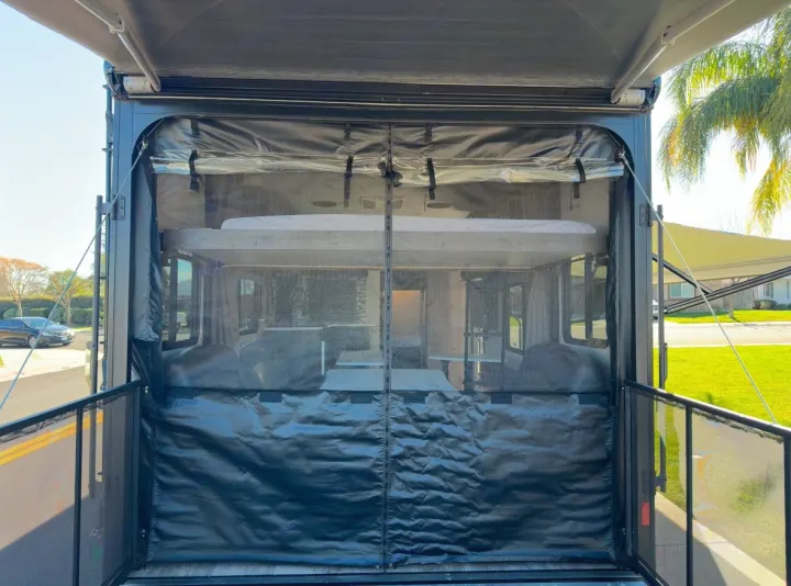 Inside an RV rental toy hauler with its ramp patio and screen room deployed, showing internal bunks.. Forest River Shockwave 2021