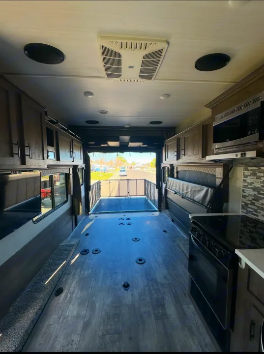 Inside RV rental: Spacious toy hauler with kitchen, convertible bed/couch, & open ramp. Ready for gear & adventure.. Forest River Shockwave 2021