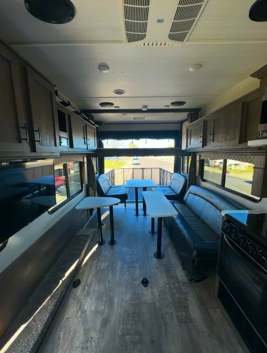 Tour this RV rental's spacious interior: dining tables, benches, a full kitchen, and unique rear ramp-patio.. Forest River Shockwave 2021