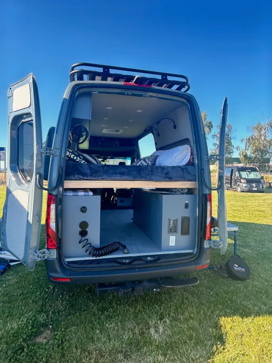 This custom RV rental offers a well-designed camper van interior with a bed, ample storage, and full utilities for outdoor adventures.. Mercedes-Benz Sprinter 144 2023