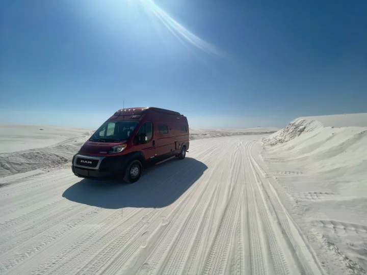 Experience a unique rv rental journey! Red campervan on stunning white sand dunes under a bright blue sky.. Winnebago Solis 2022