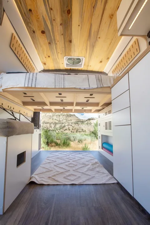 Experience comfort in this rv rental. A cozy bed, wood ceiling, and ample storage lead to scenic mountain views.. Dodge Ram 1500 2024