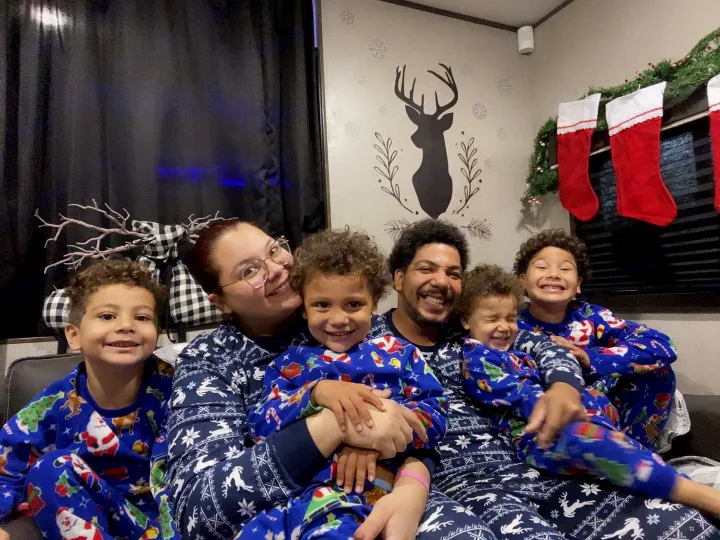 Happy family of six in matching Christmas pajamas in a festive RV rental, surrounded by holiday decorations.. Jayco Jay Flight SLX 2021