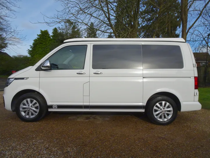 White Volkswagen campervan with pop-top roof and black racing stripes, ideal for an RV rental adventure.. Volkswagen T6.1 Campervan 2021
