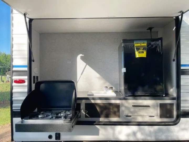 RV rental featuring a compact outdoor kitchen with a two-burner stove, sink, and mini-fridge, ideal for camping.. Crossroads RV Funtime 333sk 2024