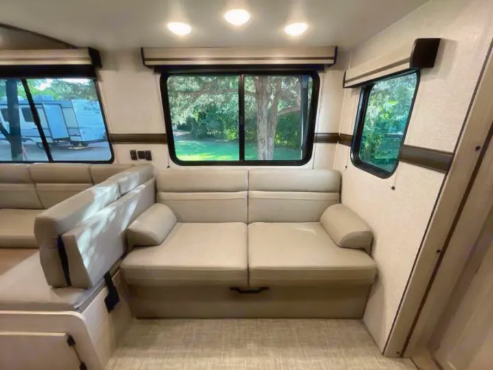 Spacious RV rental living area featuring an L-shaped sofa and large windows with outdoor views.. Crossroads RV Funtime 333sk 2024