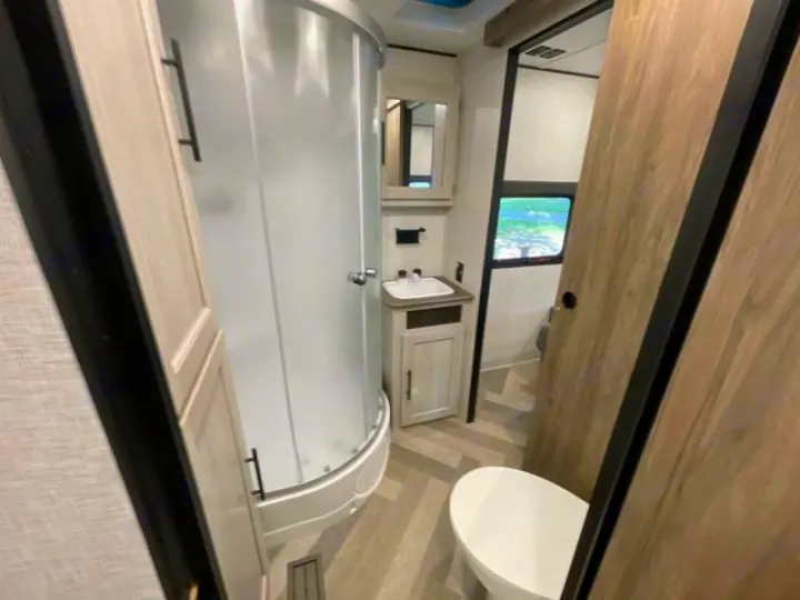 Inside an RV rental bathroom: a clean, modern space with a curved shower, sink vanity, and toilet for comfortable travel.. Crossroads RV Funtime 333sk 2024