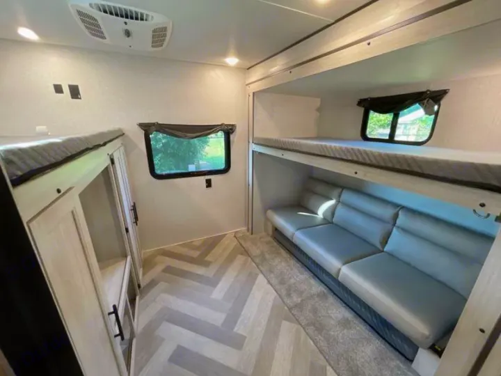Spacious RV rental interior featuring modern bunk beds, comfortable sofa, and storage. Ideal for family trips.. Crossroads RV Funtime 333sk 2024