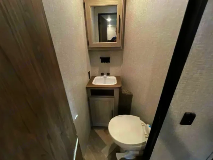 Inside an RV rental: a compact bathroom with a white toilet, small sink, and a medicine cabinet above. Practical for travel.. Crossroads RV Funtime 333sk 2024