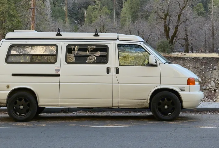 White RV rental campervan parked roadside, ready for adventure in a tranquil winter forest setting.. Winnebago Eurovan Camper Eurovan Camper 1999