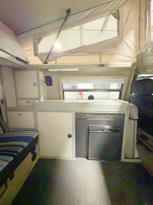 Cozy RV rental interior with pop-top, galley, Dometic fridge, and bench seating. Ready for your next road trip.. Winnebago Eurovan Camper Eurovan Camper 1999
