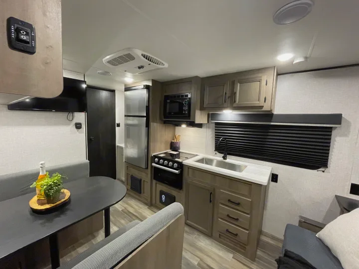 Spacious rv rental interior: modern kitchen, dining area, TV. Perfect for travel adventures.. Jayco Autumn Ridge 20MB 2023