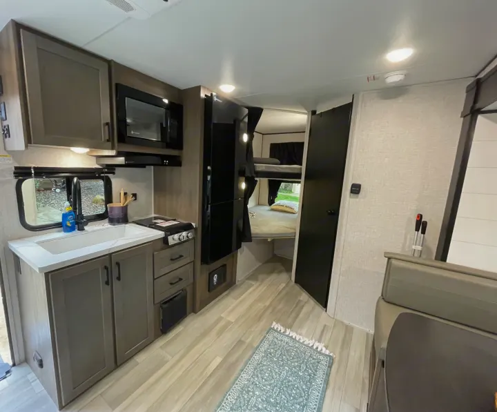 RV rental interior featuring a modern kitchen with sink, microwave, fridge, and cozy bunk beds.. StarCraft 188BHS 2025