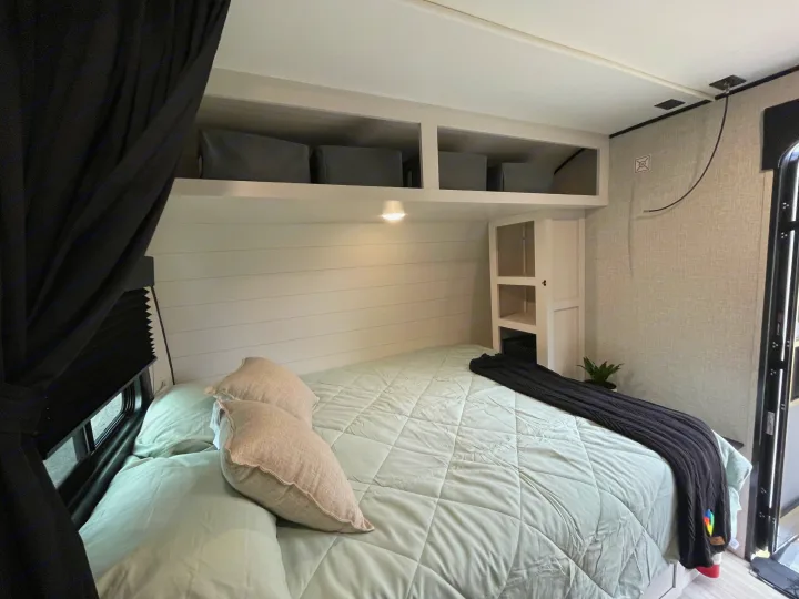 Cozy RV rental bedroom with comfortable bed, overhead storage bins, and shiplap wall for a compact yet inviting space.. StarCraft 188BHS 2025