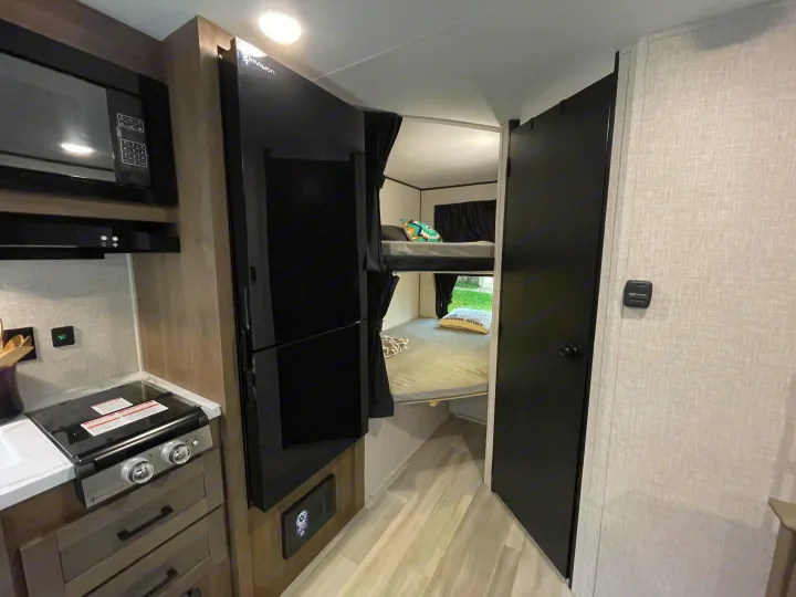 RV rental interior: compact kitchen, tall refrigerator, and cozy bunk beds. Perfect for your next adventure.. StarCraft 188BHS 2025