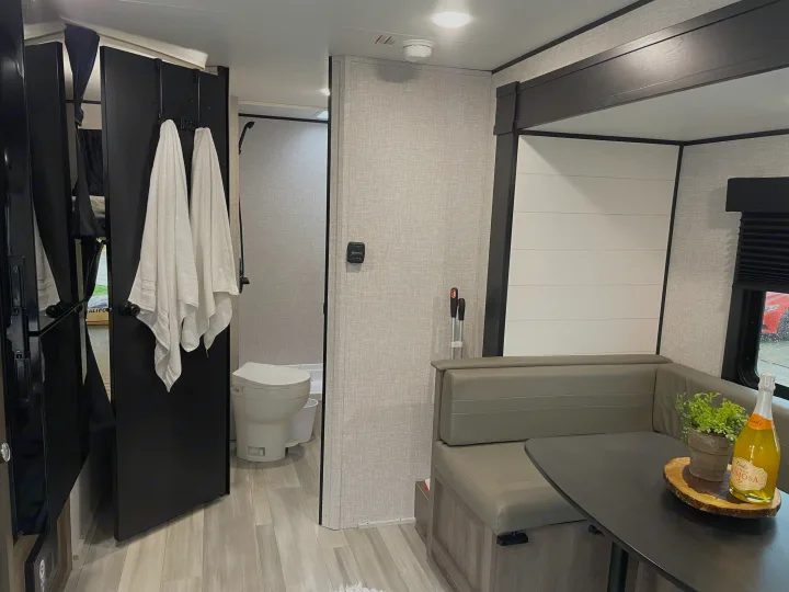 Modern RV rental interior with a cozy dining booth, table, and compact bathroom. Ideal for your next road trip adventure!. StarCraft 188BHS 2025