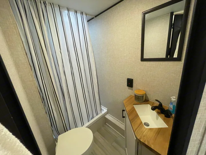 Explore this RV rental's compact bathroom with a white-and-black striped shower, toilet, and modern sink vanity.. StarCraft 188BHS 2025