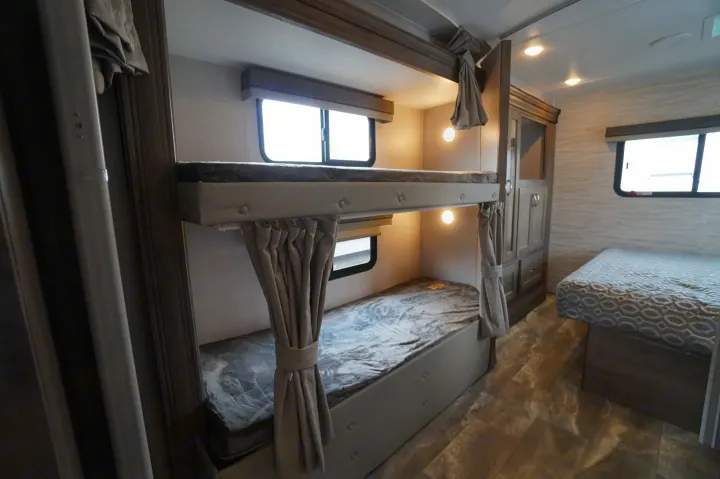 Cozy RV rental interior with bunk beds, practical storage, and a comfortable main bed. Perfect for family adventures.. Gulf Stream Conquest 2024